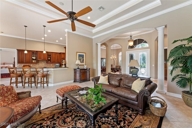 tiled living room with decorative columns, a raised ceiling, french doors, crown molding, and ceiling fan with notable chandelier