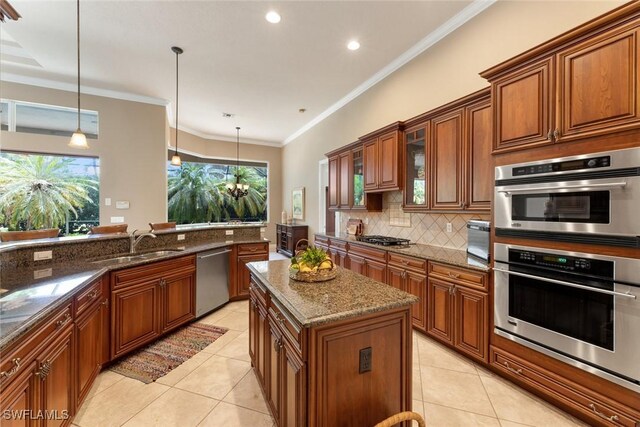 kitchen featuring decorative light fixtures, a center island, stainless steel appliances, and dark stone counters