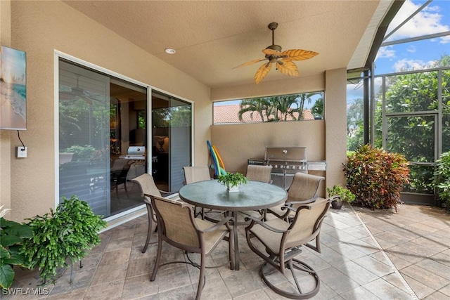 view of patio featuring ceiling fan, exterior kitchen, and glass enclosure