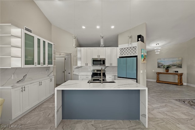 kitchen featuring a center island with sink, stainless steel appliances, pendant lighting, light stone counters, and sink