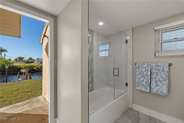 bathroom with combined bath / shower with glass door and a water view