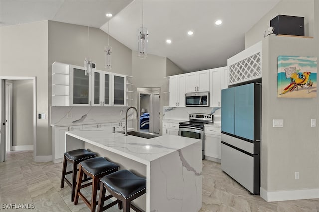 kitchen featuring pendant lighting, tasteful backsplash, a kitchen island with sink, white cabinets, and appliances with stainless steel finishes