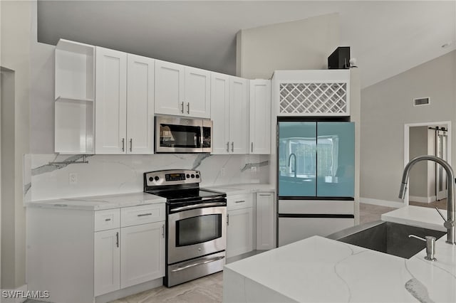 kitchen featuring white cabinets, stainless steel appliances, and light stone counters