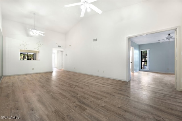 unfurnished living room featuring high vaulted ceiling and dark wood-type flooring