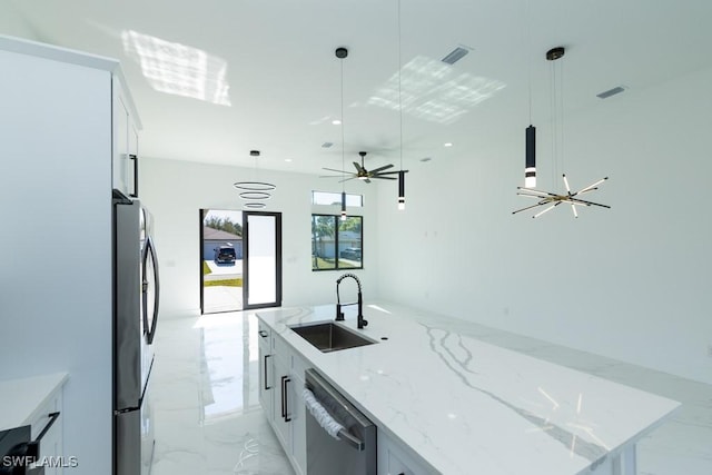 kitchen with sink, stainless steel appliances, white cabinets, a center island with sink, and decorative light fixtures