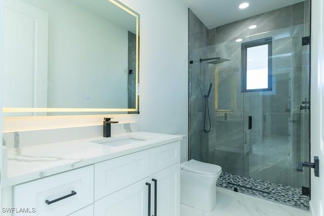 bathroom featuring vanity, a shower with shower door, and toilet