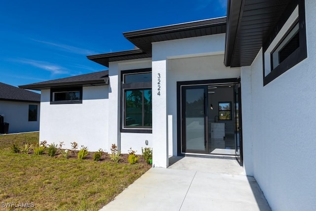 view of exterior entry with a yard and a patio area