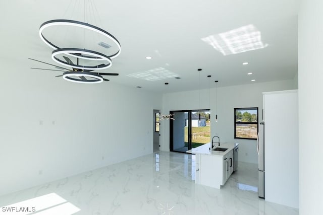 kitchen featuring white cabinetry, sink, pendant lighting, and an island with sink