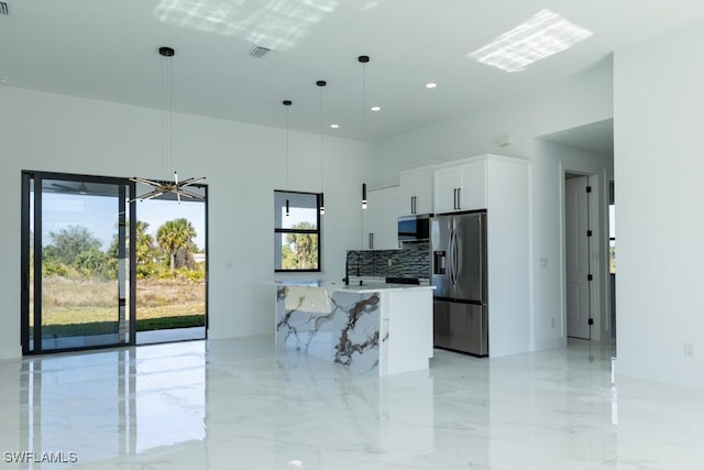 kitchen featuring white cabinetry, hanging light fixtures, stainless steel appliances, a spacious island, and decorative backsplash