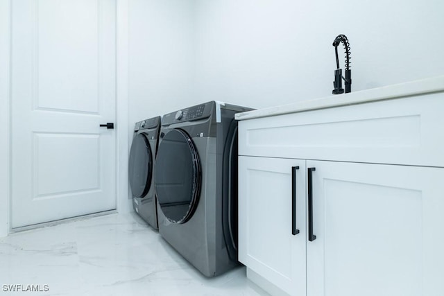 clothes washing area with cabinets and washing machine and clothes dryer