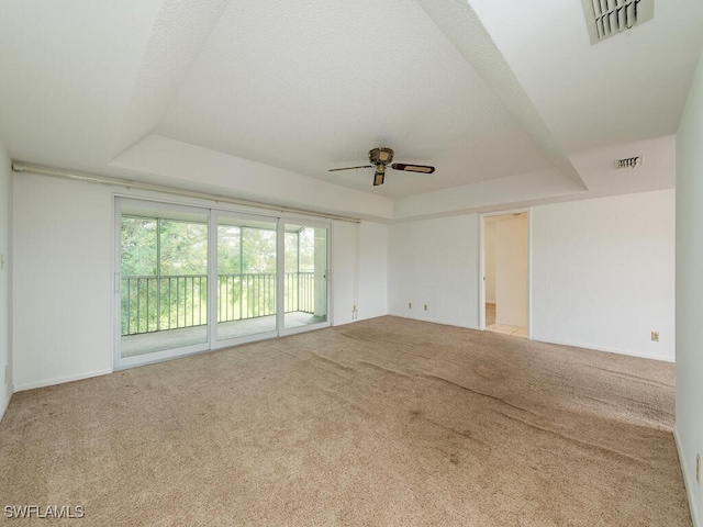 unfurnished room featuring light carpet, ceiling fan, a textured ceiling, and a raised ceiling