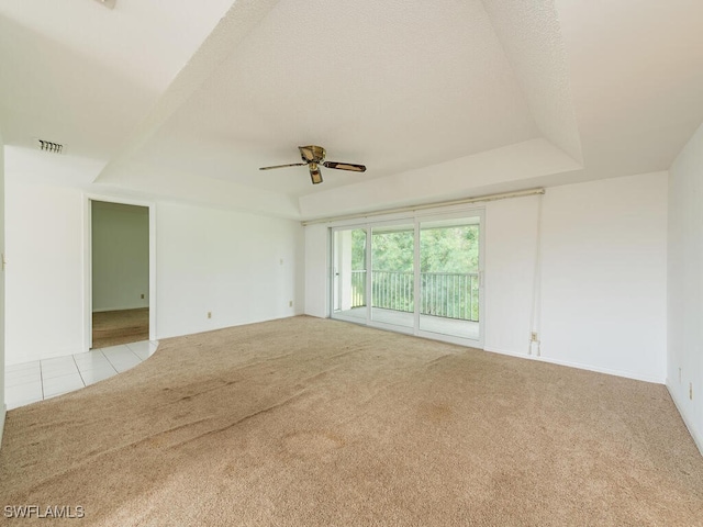 carpeted spare room featuring ceiling fan and a raised ceiling