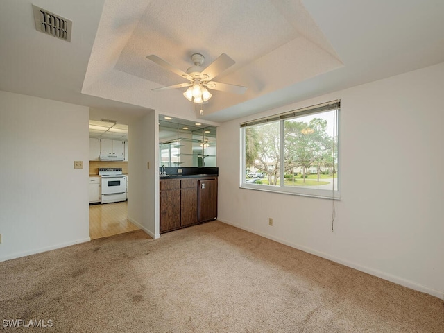 unfurnished living room featuring ceiling fan, light colored carpet, and sink