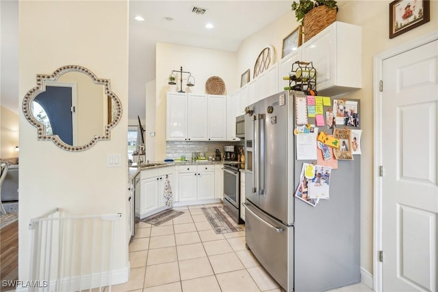 kitchen with light tile patterned flooring, appliances with stainless steel finishes, white cabinetry, sink, and decorative backsplash