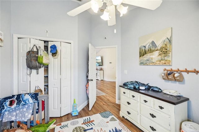 interior space with ceiling fan, a closet, light hardwood / wood-style flooring, and a towering ceiling