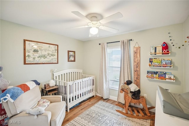 bedroom featuring a crib, ceiling fan, and light hardwood / wood-style floors