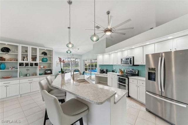 kitchen featuring sink, a breakfast bar area, appliances with stainless steel finishes, an island with sink, and white cabinets