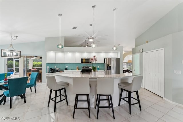 kitchen featuring stainless steel appliances, hanging light fixtures, a breakfast bar, and white cabinets