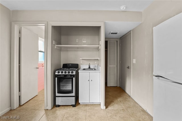 kitchen featuring light tile patterned flooring, sink, range with gas stovetop, and white fridge