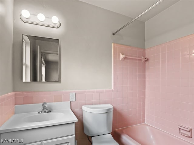 bathroom featuring tile walls, tiled shower / bath, and vanity