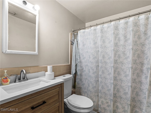 bathroom featuring toilet, vanity, decorative backsplash, and tile walls