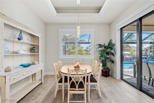 dining space with a chandelier, light wood-type flooring, and a tray ceiling