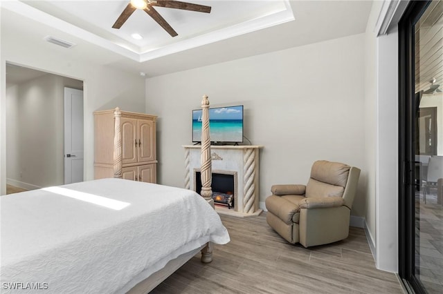 bedroom with a fireplace, a raised ceiling, and ceiling fan