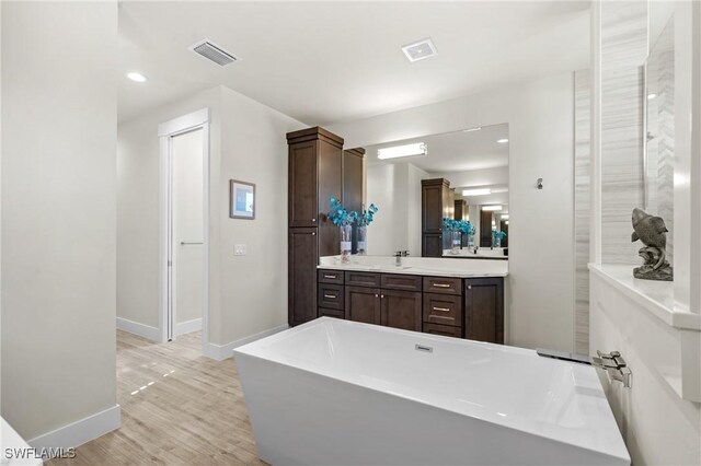 bathroom featuring hardwood / wood-style floors, vanity, and a tub to relax in