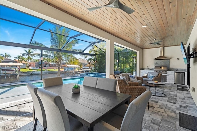 view of patio / terrace with glass enclosure, area for grilling, ceiling fan, and a water view