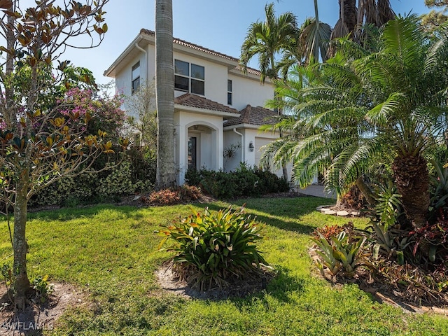 mediterranean / spanish home featuring a garage and a front yard