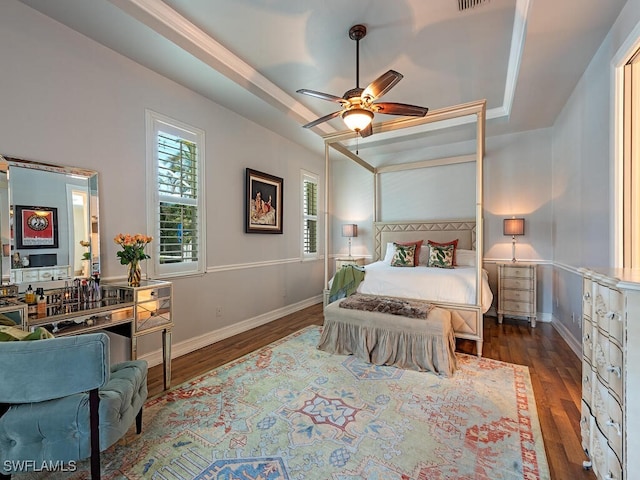 bedroom with ceiling fan, dark hardwood / wood-style floors, and a raised ceiling