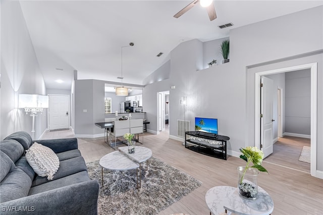 living room with ceiling fan, lofted ceiling, and light wood-type flooring