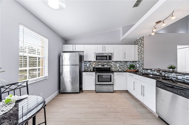 kitchen featuring lofted ceiling, tasteful backsplash, sink, stainless steel appliances, and white cabinets