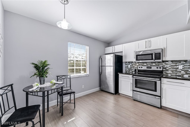 kitchen featuring stainless steel appliances, lofted ceiling, backsplash, and white cabinetry