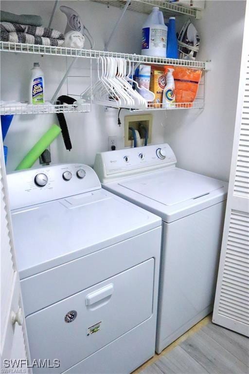 laundry room with washer and dryer and light wood-type flooring