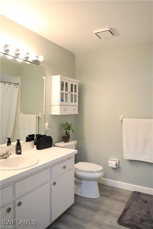 bathroom featuring wood-type flooring, vanity, and toilet