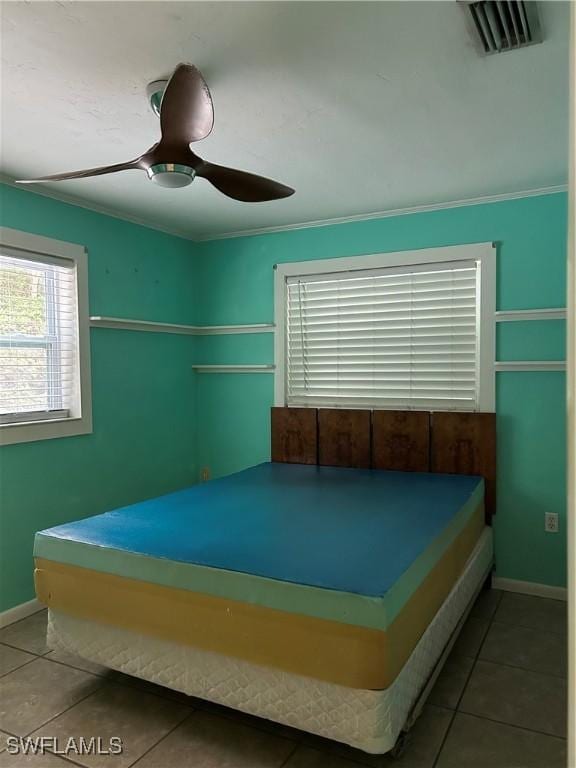 tiled bedroom with ornamental molding and ceiling fan