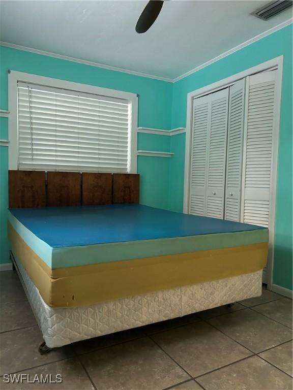 unfurnished bedroom with crown molding, a closet, and ceiling fan