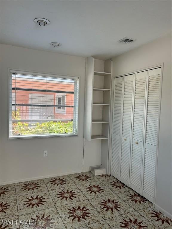 unfurnished bedroom featuring a closet, visible vents, and baseboards