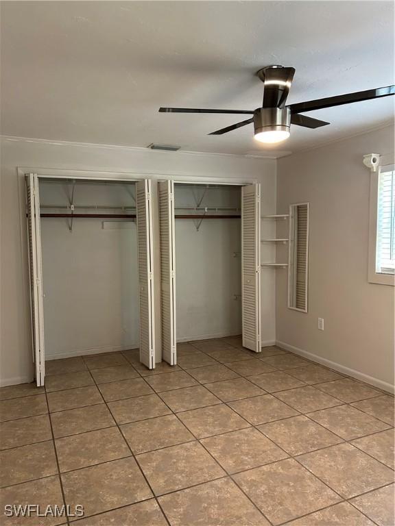 unfurnished bedroom featuring visible vents, two closets, a ceiling fan, light tile patterned floors, and baseboards