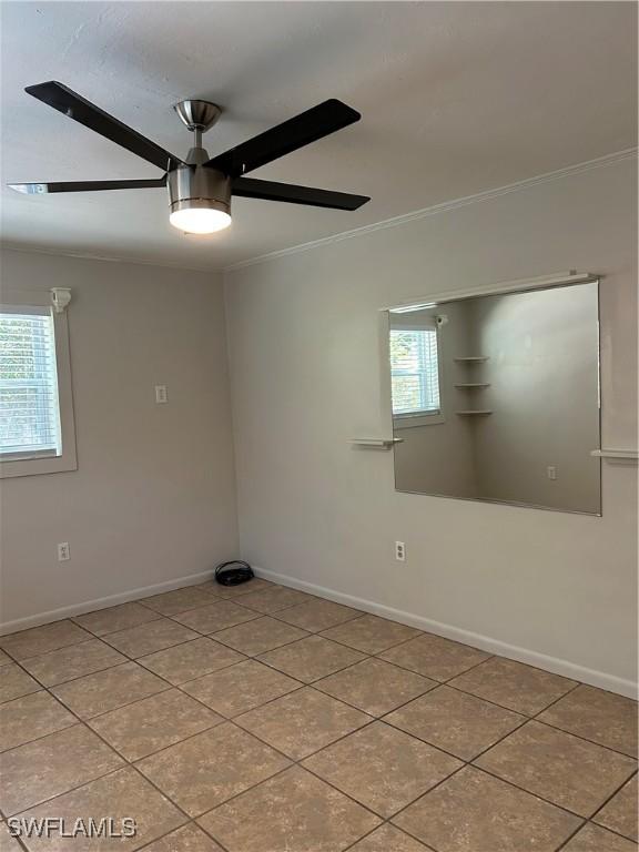 spare room with a wealth of natural light, baseboards, crown molding, and ceiling fan