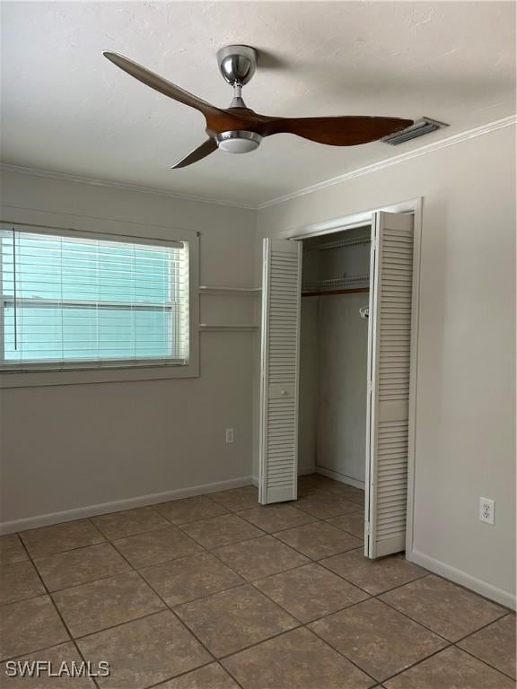 unfurnished bedroom featuring visible vents, tile patterned floors, crown molding, baseboards, and a closet