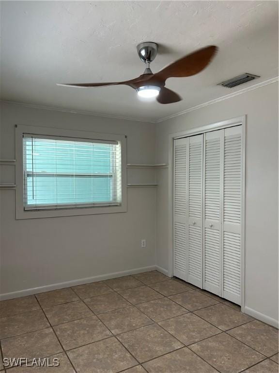 unfurnished bedroom with a closet, visible vents, multiple windows, and crown molding