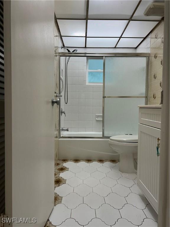 bathroom with toilet and shower / bath combination with glass door