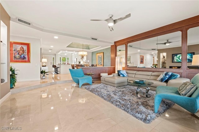 tiled living room featuring ornamental molding, ceiling fan with notable chandelier, and a raised ceiling