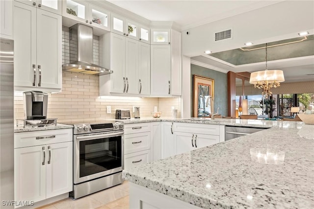 kitchen with white cabinetry, appliances with stainless steel finishes, hanging light fixtures, wall chimney range hood, and sink