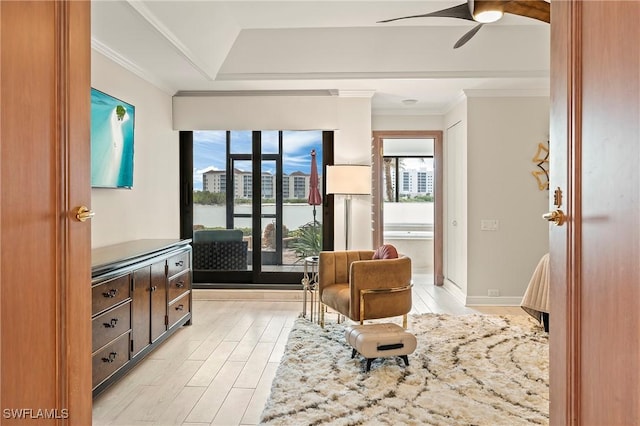 sitting room with light wood-type flooring, ceiling fan, and crown molding