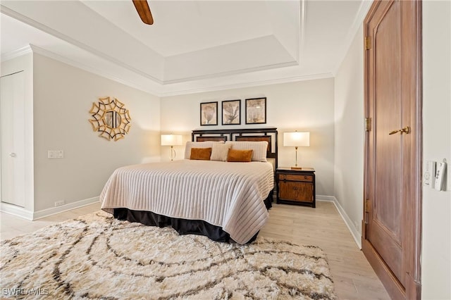 bedroom with a raised ceiling, ceiling fan, ornamental molding, and light hardwood / wood-style flooring