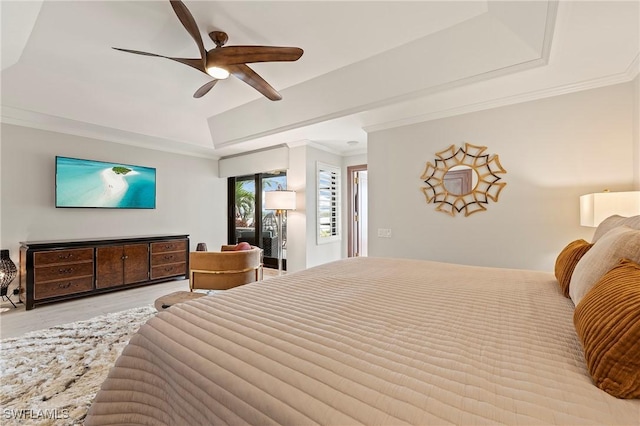 bedroom featuring ceiling fan, a tray ceiling, ornamental molding, and light wood-type flooring