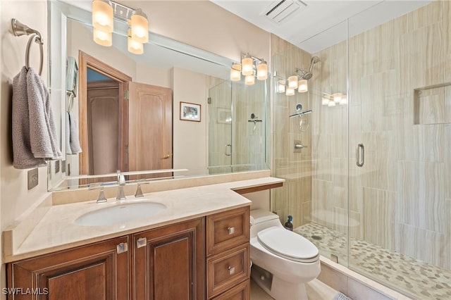 bathroom featuring toilet, a shower with door, and vanity